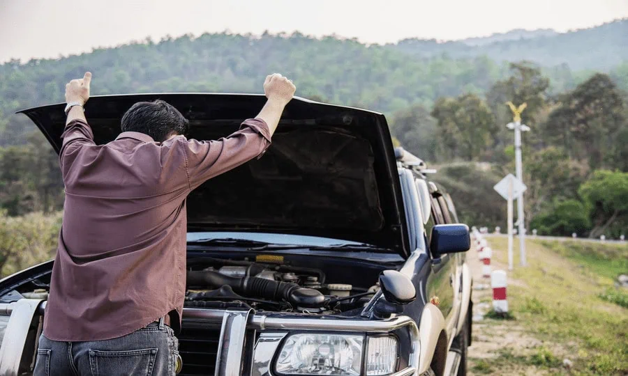 stalled car with man looking under the hood