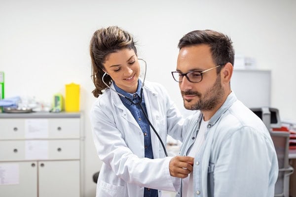 female doctor checking heartbeat of male patient